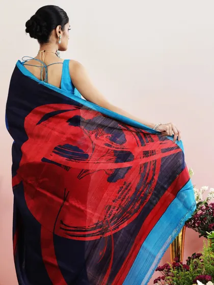 A stunning saree with an abstract print in shades of blue, red, and green. The pallu features a bold, artistic design.
