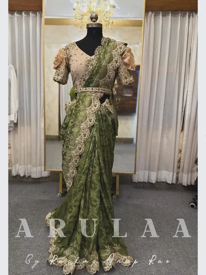 A full view of a custom-designed reception saree on a mannequin. This sap green organza saree is paired with a cream blouse and features heavy scalloped embroidery.
