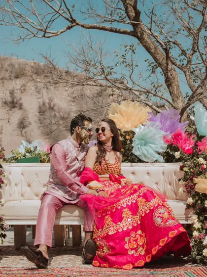A vibrant Haldi celebration set against a stunning mountain backdrop. The couple, covered in turmeric, shares a happy moment, showcasing the fun and festive atmosphere of the day.