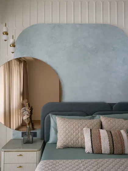 A close-up of the serene luxury master bedroom in a calming sage green palette. The curved design element with texture paint and a tinted mirror panel adds depth and visual interest.