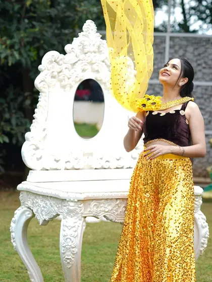This shot captures a playful moment during a fashion shoot. The makeup is radiant and enhances the model's features, working in harmony with the bright, sunny colors of her outfit.