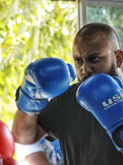 A fighter with an intense look, ready to spar. The atmosphere in the gym is serious but supportive.