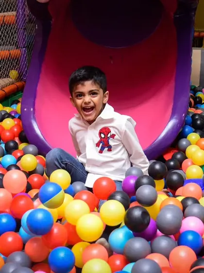 A huge, happy smile from a boy enjoying his time in the ball pit.