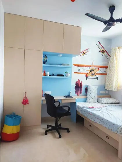 An aviation-themed kid's room with a custom wardrobe that includes an integrated study nook. The wall mural of vintage planes sparks imagination and adventure.