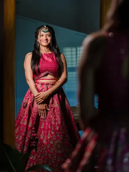 The bride looks in the mirror, admiring her festive look for the Mehendi ceremony, ready for an evening of celebration.