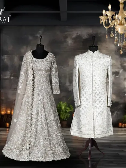 A complete look of modern elegance. The groom's off-white sherwani, with its unique geometric and leather work, stands as a statement of contemporary style, perfectly complementing the bride's flowing floral gown.