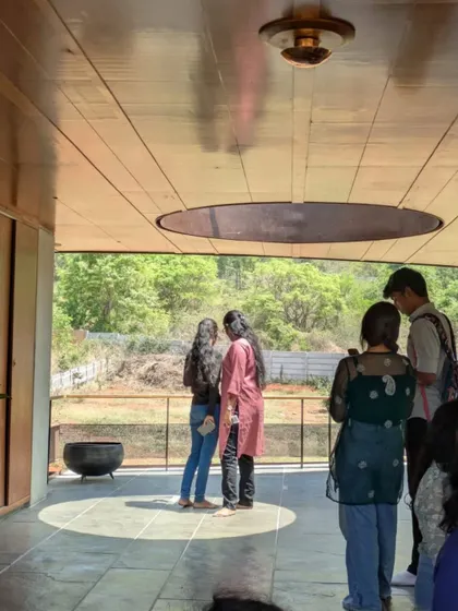 A small group of students standing on the veranda, experiencing the interplay of light and shadow created by the architectural canopy. These moments of quiet observation are crucial for developing a sensitivity to atmosphere and spatial quality.