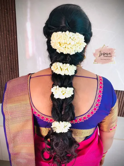 A traditional messy braid hairstyle using strands of fresh jasmine flowers. This classic look is fragrant and timeless, perfect for any South Indian ceremony.