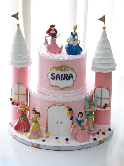 A princess castle cake fit for royalty. This cake for Saira's 3rd birthday features multiple Disney princesses around a beautiful pink castle with towering turrets.