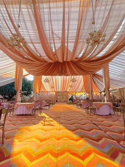 A wide view of a tented wedding reception, showing the colorful chevron-patterned floor and elegant drapery.