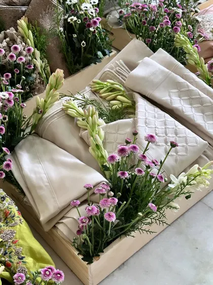 A tray with elegant cream-colored outfits, decorated with fresh flowers. The subtle colors and natural elements create a sophisticated and timeless look.