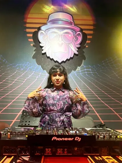 Posing at the Pioneer DJ console at a corporate gig. The retro-themed background with the funky monkey logo added a cool touch to the night's setup.