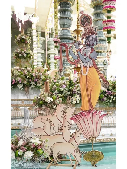A life-sized cutout of Krishna serenading his cows, set amidst lush florals. This artistic element was a key part of our 'Brindavan of love' theme, bringing a narrative touch to the wedding decor.