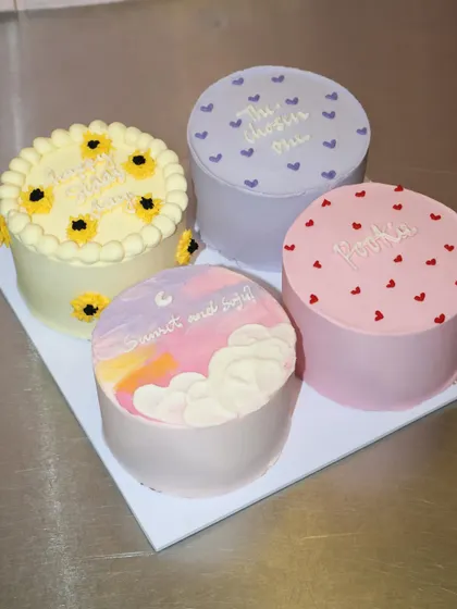 A soft and sweet collection of four mini cakes with different pastel designs. This set includes a beautiful sunset sky, a sunflower-themed cake, and simple heart patterns, perfect for a gentle and heartfelt gift.