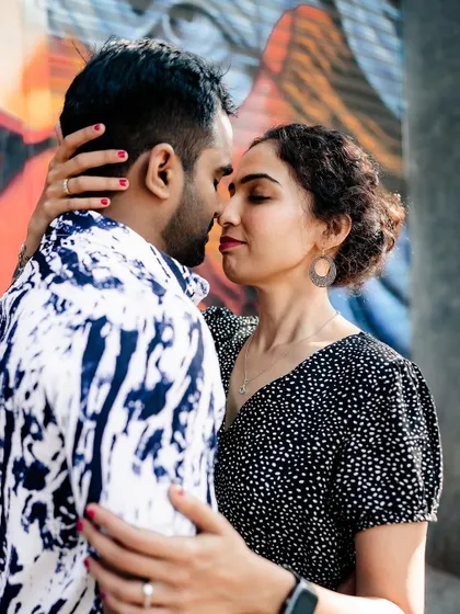 A close-up, intimate moment between the couple in front of a vibrant graffiti wall.