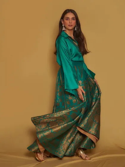 A full-length shot of the emerald green Payal Khandwala fusion look. The flowing brocade skirt paired with a simple silk shirt is the epitome of modern luxury.