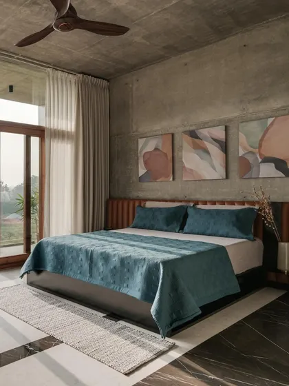This bedroom in The Quarry House uses exposed concrete walls as a backdrop. The minimalist design is softened by a leather headboard and abstract art.