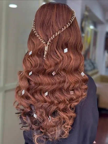 A beautiful open hairstyle with rich, colored waves. The look is accessorized with a modern, snake-like hair chain and scattered diamond-shaped clips.