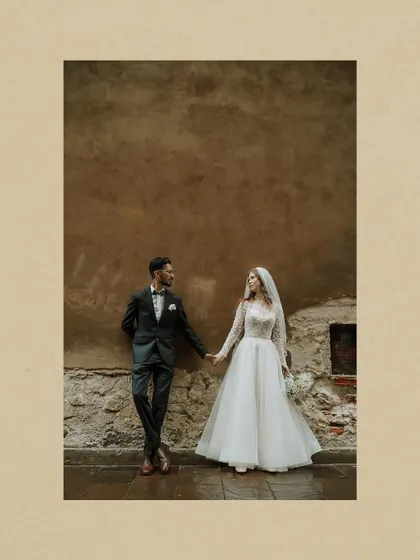 A romantic, artistic shot of the couple holding hands against a rustic European wall. It highlights the quiet, intimate moments of their international love story.