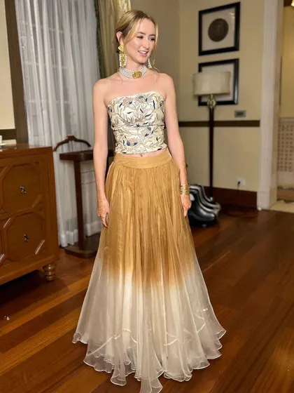 A full-length shot of the sister of the bride in a contemporary Indian outfit. Her hair is styled in an elegant updo, and the makeup is fresh and glowing.