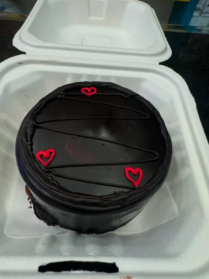 A rich chocolate bento cake with simple red heart decorations. It's a classic choice for a quick and delicious celebration for any chocolate lover.