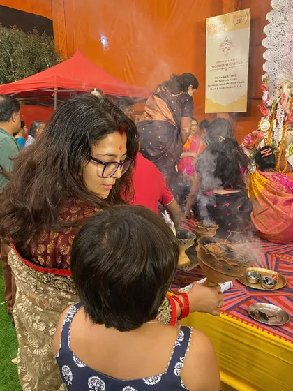 A different angle of the family at the Durga Puja festival, showing the mother guiding her child. These photos document shared experiences and the passing down of traditions.
