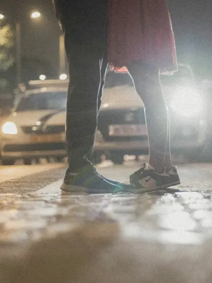 A low-angle shot focusing on the couple's feet on a crosswalk, with city traffic in the background. A unique perspective on a city romance.