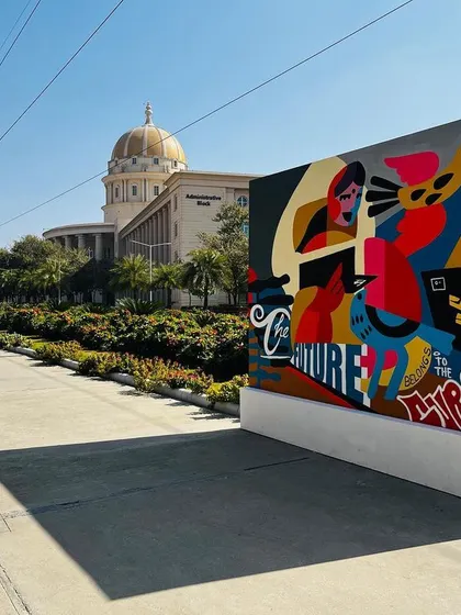 The abstract canvas placed on the university grounds. Its vibrant colors and modern design stand out, creating a popular spot for students to gather and take photos.
