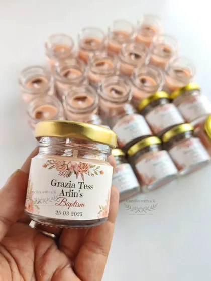 A close-up of the personalized mini jar candle for Grazia Tess Arlin's Baptism, showing the custom floral sticker.