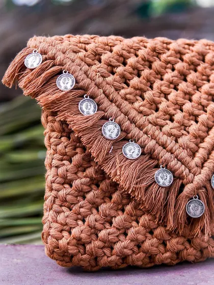 Here's a closer look at the beautiful details on my tan coin clutch. You can see the intricate knot work and the delicate silver-toned coins that I've added to the fringe. It's these little touches that make each handmade bag so special.