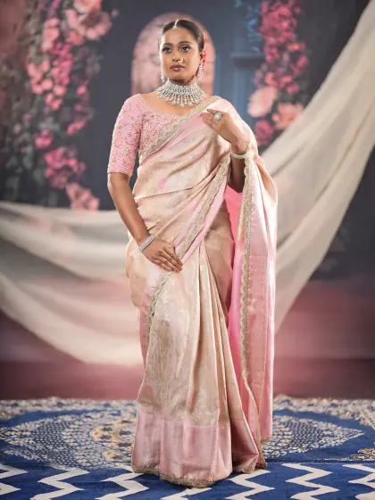 A full-length shot showing the complete ensemble. The soft glam makeup perfectly complements the elegant pink and cream saree.