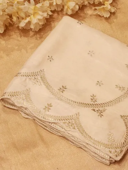 The delicate scallop border of the Tussar silk saree, intricately hand-embroidered with silver zari.
