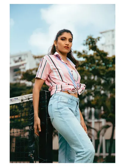 A casual outdoor portrait on a tennis court. The setting adds a sporty, lifestyle element to this fashion-forward shot.