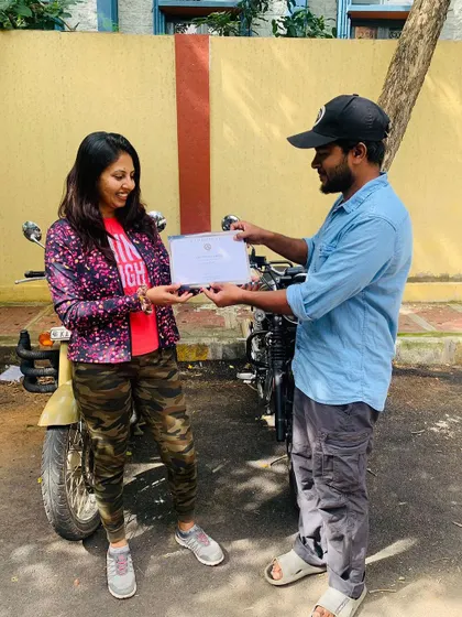 The official handover. A student receives her Certificate of Accomplishment, marking the successful completion of her beginner motorcycle training.