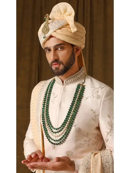 A close-up of the Jashn-e-Ada sherwani, focusing on the delicate floral threadwork and the elegant emerald mala that completes the look.