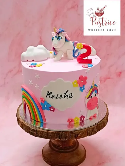 A pretty pink unicorn cake with a rainbow and floral details, perfect for a magical second birthday.