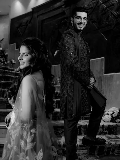 A stylish black and white portrait of the couple on a staircase during their Sangeet event.