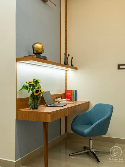A compact and stylish floating desk in a bedroom, creating a perfect nook for work or study. The design is complemented by a comfortable blue swivel chair and task lighting from an integrated LED strip.