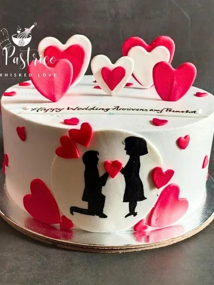 A close-up of the anniversary cake, showing the detail of the edible hearts and the couple's silhouette.