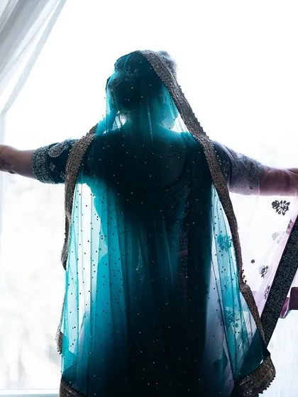 A silhouette of the bride against a bright window, creating a dramatic and artistic portrait that focuses on her form and veil.