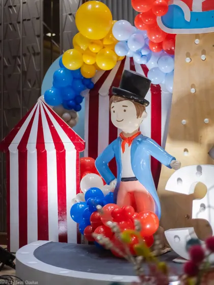 A close-up of a ringmaster prop at a carnival-themed party. This character, along with the red-and-white striped tent prop and colorful balloons, adds to the authentic circus atmosphere.