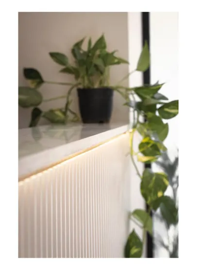 The soft, ambient light from the hidden LED strip creates a gentle highlight on the textured wall panel.