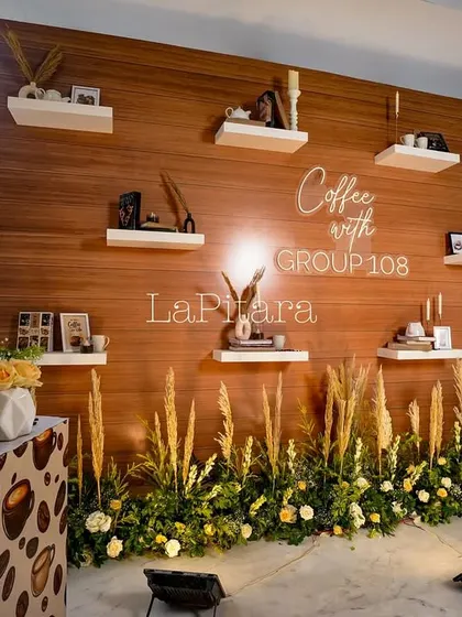 We created this beautiful photo wall with a wood-paneled backdrop and floating shelves. Each shelf was styled with coffee-themed decor, books, and candles, providing an elegant and on-theme photo opportunity for guests.
