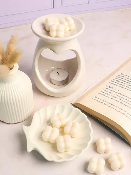 A perfect reading nook setup featuring our heart diffuser, shell-shaped trinket dish, and mini bubble wax melts. Unwind and indulge in enchanting scents.