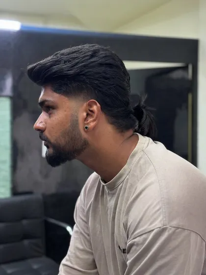 This modern mullet features a low fade and a small ponytail at the back. It's a versatile way to wear the style, allowing you to tie it up or let it flow.