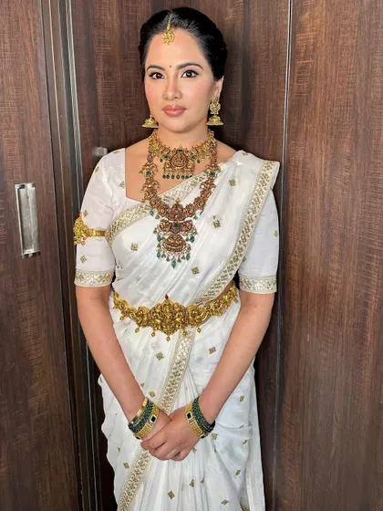 A vision in white and gold. This traditional look for a pre-wedding pooja is pure elegance, with classic temple jewelry and a clean makeup look.