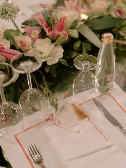 A close-up of the place setting from an elegant wedding dinner. Every detail, from the custom menu to the fine cutlery and floral arrangements, was planned to perfection.