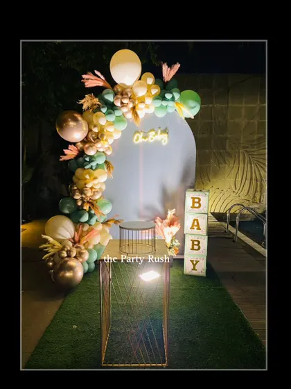 This elegant baby shower decor features a sophisticated color palette of sage green, gold, and white. The "Oh Baby" neon sign and "BABY" blocks add a modern and celebratory touch to the poolside event.