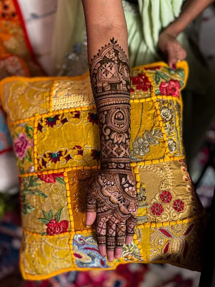 A close-up of one arm, showing the detailed Ambari elephant and other intricate patterns.