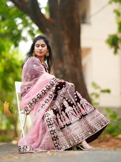 A seated portrait showing the detailed embroidery on the velvet lehenga. The craftsmanship is clearly visible, making it a great choice for close-up shots.